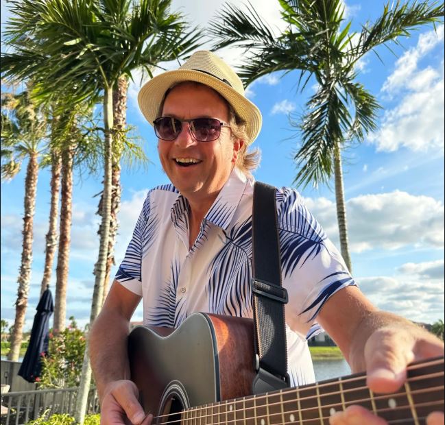 Gary Bradley smiling with his acoustic guitar